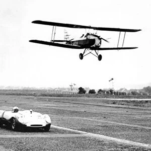 A Tiger Moth aircraft and a Lotus Ford 23B, racing at Usworth Aerodrome 1963