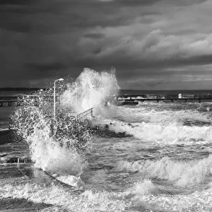 Waves Crashing Along The Coast With A Small Lighthouse At The End Of A Pier; Amble, Northumberland, England