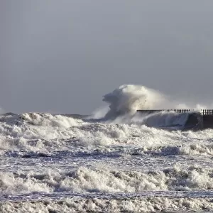 Waves Crashing Against A Pier With A Lighthouse