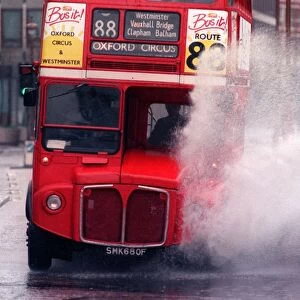 A bus splashing through a large puddle of water after a heavy rainfall in London