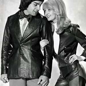 Male and female model linking arms and looking at each other both wearing leather jackets
