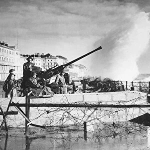 Sea spray breaks over a South Coast sea front wall on to an anti aircraft gun crew during