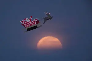 A 10-foot long remote controlled flying Santa makes a test flight past a setting moon