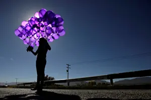 Activist holds purple balloons at El Navajo creek during a ceremony to mark