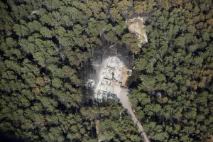 Fire Prints: An aerial view of a destroyed house surrounded by dense forest in the aftermath of