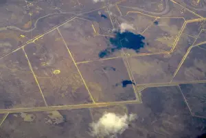 An aerial view of intersecting roads and dams amongst agricultural farming land in