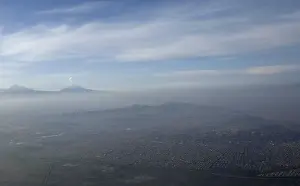 An aerial view of Mexico City is seen, with the Popocatepetl volcano in the background
