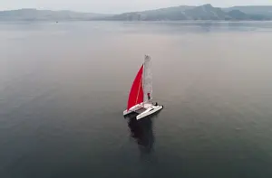 Aerial view shows a couple traveling on a sailing catamaran along the Yenisei River