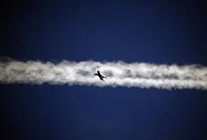 An aeroplane flies underneath the jet stream of another aircraft above the Italian city