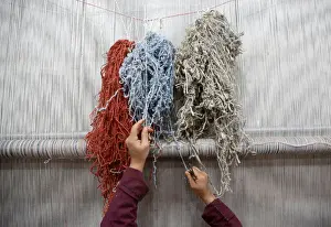 An Afghan woman reaches for a thread while working at the Afghanistan Rug