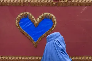 An Afghan woman walks past a decoration on the side of a traditional Reksha motor-taxi