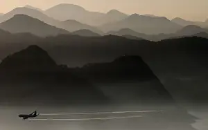 An airplane flies near mountains, as the sun rises in Rio de Janeiro