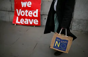 Anti-Brexit supporter stands in front of a pro-Brexit sign in London