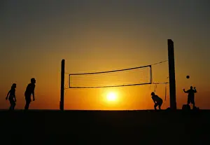 Beachgoers play volleyball at the beach as the sun sets in Carlsbad, California