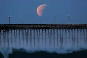 Lunar Prints: A Blue Moon comes out of a lunar eclipse as it sets past an ocean pier in Oceanside