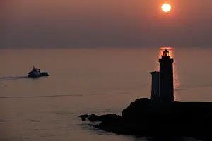 A boat makes his way behind the Phare du Petit Minou as the sun sets over the Atlantic