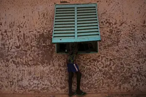 A boy peers through a window to watch electoral officials count ballots at a polling