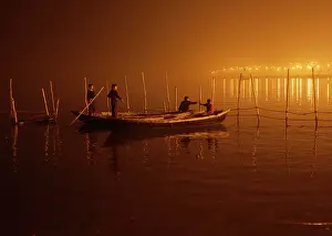 Boys tie their boats as fog covers the banks of the Yamuna river on a cold evening