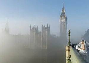 United Kingdom Prints: A bride poses for a photograph on Westminster Bridge as the fog clears in central London