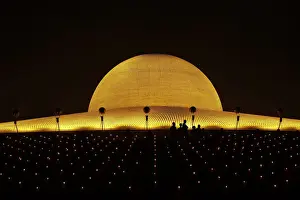 Buddhist monks hold candles and pray at the Wat Phra Dhammakaya temple in Pathum Thani province
