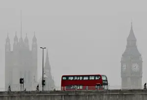 A bus crosses Waterloo bridge in front of the Houses of Parliament during a misty
