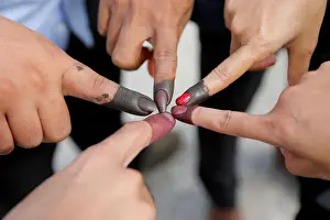Cambodian voters take pictures of their ink stained fingers after they voted