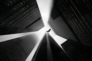 The Canadian flag is seen on top of a flagpole in the midst of high-rise buildings