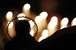 Chile Prints: Candles are seen lit behind a religious statue in front of which relatives pray for