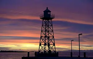 Prints of A couple stand beside a lighthouse, which is silhouetted during sunset at the Weser river in Bremerhaven, late September 8, 2013. Picture taken September 8 Germany Prints: A couple stand beside a light house, which is silhouetted during sunset at the Weser