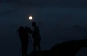 A couple takes a picture of the supermoon rising over Ischigualasto Provincial Park in San Juan