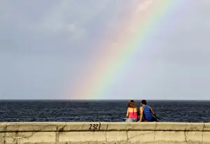 Cuba Prints: A couple watches a rainbow from Havanas seafront boulevard El Malecon