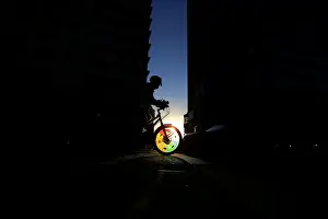 A cyclist rides into a shaft of light between two buildings in Sydneys business district