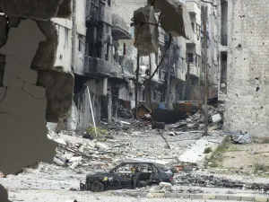 A damaged car is seen near carpets erected as protection from snipers along a street at A damaged car is seen near carpets erected as protection from snipers along a street at