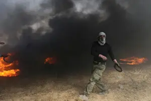 : Demonstrator passes by burning tires during clashes with Israeli troops at a protest