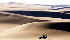 A DESERT TERRAIN VEHICLE CROSSES THE SAND DUNES AT SIWA OASIS IN EGYPT
