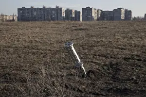 Emptied cluster munitions container is seen stuck in the ground outside apartment blocks