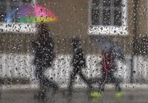 Prints of A family is seen through raindrops on a window as they shelter under umbrellas during a rainstorm in London, February 16, 2015 Britain Prints: Family is seen through raindrops on a window as they shelter under umbrellas during a