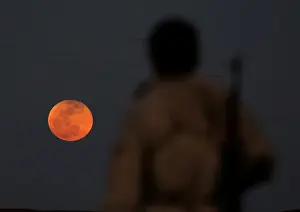 A fighter from Free Syrian Army is seen watching a full moon rises in Daraa