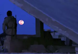 Lunar Prints: A fighter from Free Syrian Army is seen watching a full moon rises in Daraa