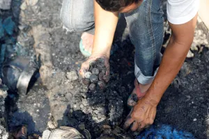 Philippines Prints: A fire victim gathers burnt coins on the ground inside the ruins of his familys home