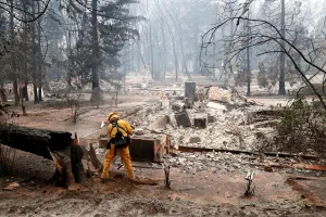 California Prints: A firefighter extinguishes a hot spot in a neighbourhood destroyed by the Camp Fire in