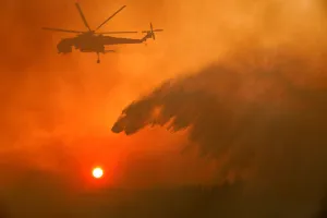Greece Prints: A firefighting helicopter makes water drop as a wildfire burns near the village of