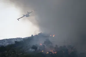 A firefighting plane drops water to extinguish a wildfire in the village of Mravince near A firefighting plane drops water to extinguish a wildfire in the village of Mravince near