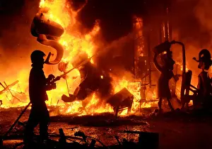 Culture Prints: A fireman sprays water at figures of a monument as it burns during the finale of