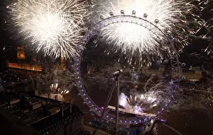 Fireworks explode beside the London Eye and The Houses of Parliament on the River