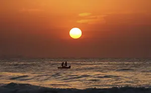 Fishermen pull their fishing net from the waters of Bay of Bengal during sunrise in