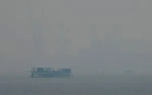 Indonesia Prints: A fishing kelong is pictured, in front of cranes at a Malaysian shipyard shrouded by haze