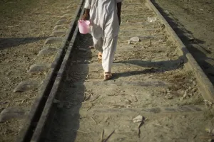 Pakistan Prints: Flood victim carries a bucket while walking on a railway next to a relief camp in
