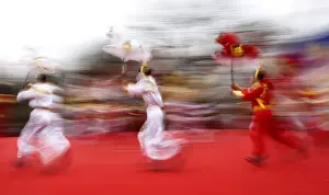 Folk dancers holding horse models perform their traditional horse dance on the first