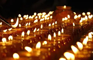 A follower lights a candle during The Grand Anniversary Memorial Prayer of Lord Jigten